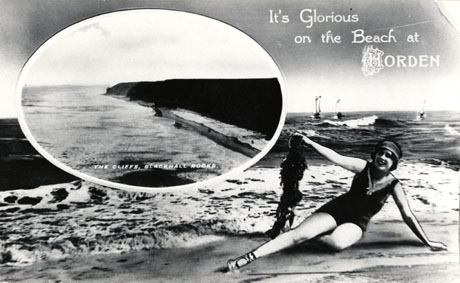 Postcard entitled It's Glorious on the Beach at Horden, showing a woman, in a bathing costume, sitting on a beach holding a piece of seaweed; inset is a picture of the cliffs at Blackhall Rocks, showing the cliffs at Blackhall, the shore and the sea