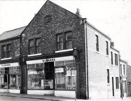 Photograph of the exterior of Kilburns shop showing the shop windows, of which there are two side by side; one window contains a perambulator and a cot; another women's dresses; it is difficult to see the items in the other windows but it may be furniture; the shop is described as being on Blackhills Road, Horden