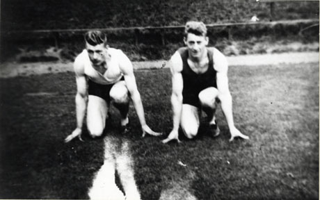 Photograph showing two men dressed in running shorts and singlets kneeling facing the camera about to start a race; the men have been identified as Bob and Ralph Porter