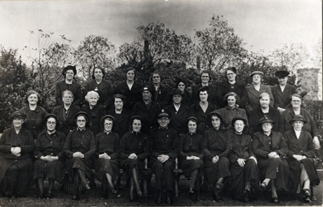 Photograph of a group of twenty nine women and one man posed against bushes and trees; six of the women, and the man, are wearing the uniform of the Salvation Army; the photograph has been identified as portraying the Salvation Army at Horden