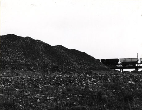 Photograph entitled Railway Trucks, Horden, 1976 showing a spoil heap and, in the left-hand side of the photograph, two trucks on a rail in the middle distance