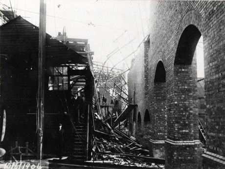 Photograph of the engine house at Horden Colliery under construction, showing, at the right of the photograph, a brick wall with arches in it partly constructed, with wood, possibly discarded scaffolding, lying in front of it; a wooden building on the left of the photograph has two men coming down its stairs; the date of 10 June 1904 is written on the photograph