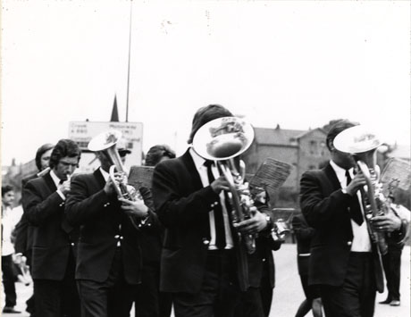 Photograph of seven members of Horden Band playing their instruments in the City of Durham during the Miners' Gala; the players are shown close- up, but their faces are obscured by their instruments