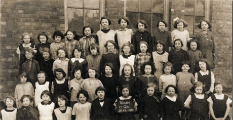 Photograph of a group of forty four girls aged approximately ten years posed outside a brick building; a girl on the front row is holding a notice reading; Horden Council Girls Standard 4b 1927