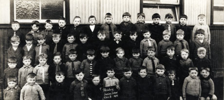 Photograph of a group of fifty two small boys, aged approximately seven years, posed in front of a wooden building; a child on the front row is holding a notice which reads: Horden Junior School Class 3 1927