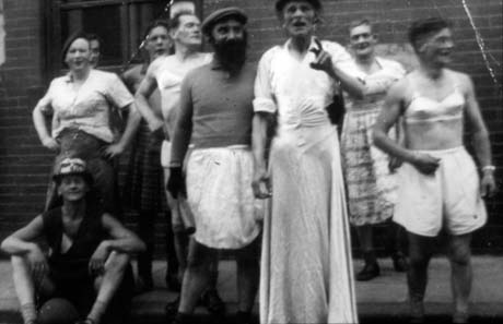 Photograph showing nine men dressed as women; two are wearing bras and pants, one is wearing a long frock, another a pinafore; the occasion for the dressing up has not been established, but they have been identified as being in Horden