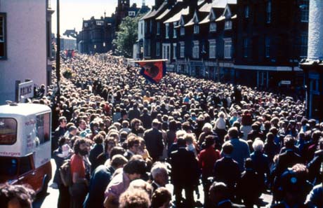 Photograph showing Old Elvet in Durham City with the side of The Royal County Hotel on the left,looking towards the end where the prison is; Old Elvet is completely covered by crowds and two indistinct banners can be seen being carried by the crowds; a van selling Hot Dogs can be seen on the left