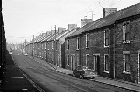 Photograph showing one side of a road running away from the camera, consisting of terraced houses; three cars are parked on the road, which has been identified as Colliery Street, Horden