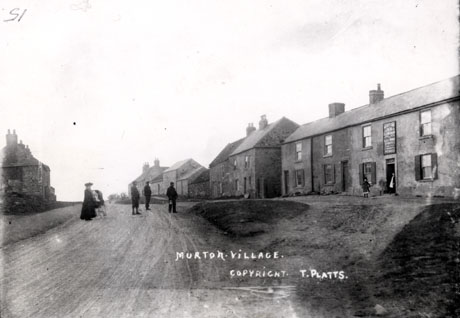 Postcard photograph entitled Murton Village. Copyright. T. Platts., showing a road running away from the camera with a woman and a perambulator and three men standing in the road; the side of a building is on the left; on the right, the facade of the Murton Inn with two girls standing in its doorway can be seen; beyond the inn are three houses and six barns