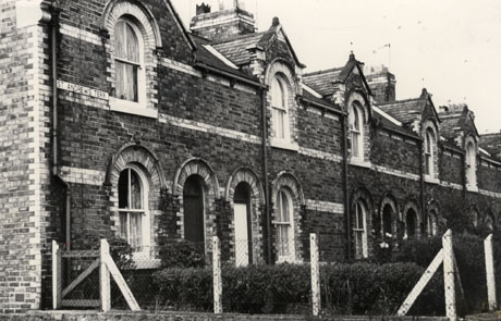 Photograph of the exterior of the front of a terrace of houses with one round-headed window on the ground and first floors; the doorway also has a round head; the windows and doorway are picked out in coloured brick and bands of coloured brick run along the front of the houses, which have been identified as St. Andrew's Terrace, Horden