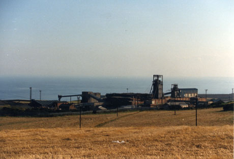Photograph showing a colliery near the sea seen across fields; low buildings and two winding gear can be seen; it has been described as Horden Colliery, but it is more likely that it is Easington Colliery