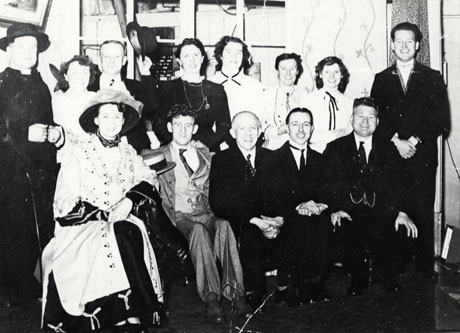 Photograph of the thirteen members of the cast of an unidentified production by the Drama Club, Murton; the costumes appear to be those worn in the latter years of the nineteenth century and the characters include a clergyman, a fashionable lady, a governess or housekeeper and a number of conventional gentlemen