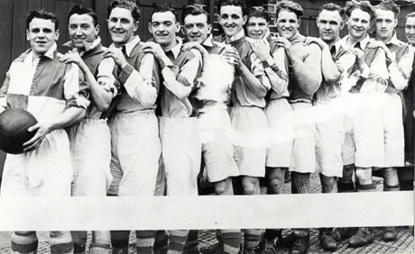 Photograph of eleven men in football strip standing sideways to the camera in a line with their hands on each others' shoulders; the face of a twelfth man can be seen at the right of the photograph; they have been identified as Murton Knaresborough Football Team