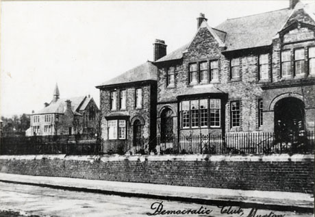 Postcard photograph entitled Democratic Club, Murton, showing the exterior of the club building on the right of the picture; a large brick building with two bay windows and a large doorway can be seen; beyond the club another substantial building and a church can be seen