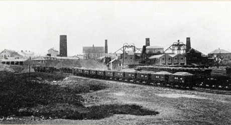 Photograph showing the colliery at Murton with a line of trucks full of coal across the left hand side of the photograph; the colliery buildings are in the distance and show three chimneys and two winding gear