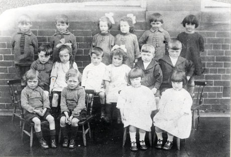 Photograph of sixteen children aged between approximately two and six years posed against a wall standing and sitting on chairs; they have been identified as Eight Sets of Twins, Murton Colliery Infants' School, 1925
