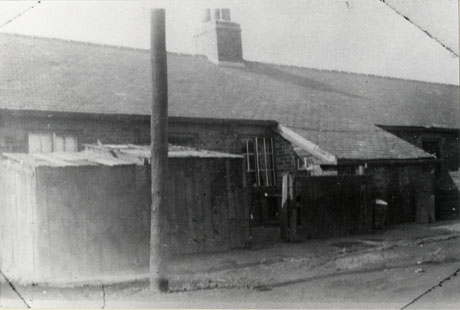 Photograph of a row of one-storeyed buildings showing the roof of the row and the roof of a lean-to at the back of the buildings; a window, and the top of another window, in the building can be seen ; part of a fence and a shed can also be seen; the buildings have been identified as Old Colliery Cottages, Murton