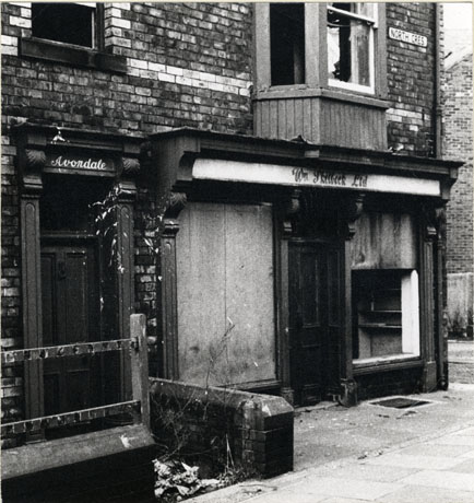 Photograph of the exterior of the shop of Wm. Skilbeck Ltd. and a doorway ,with the name, Avondale, above it; the sign bearing the name of the road, North Crescent, is on the wall above the shop; the properties are unoccupied and in a dilapidated condition; the property has been identified as being in Cold Hesledon and having been abandoned after a Clearance Order