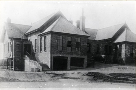Photograph of the exterior of St. Joseph's Roman Catholic School, Murton, showing a large brick building with two wings, an outside staircase and rough ground in front