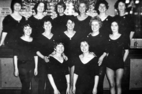 Photograph showing fourteen women in leotards posed in three rows in front of a closed bar, designed to sell alcoholic drinks; they have been described as members of Keep Fit - Joan Strong, Murton