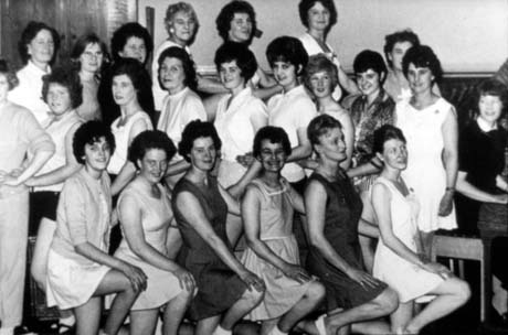 Photograph showing twenty one women in short tunics standing in three rows with their knees raised; they have been identified as members of Keep Fit - Joan Strong, Murton
