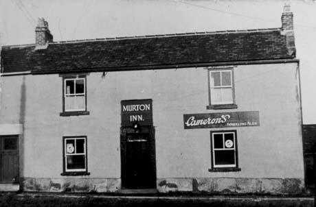 Photograph of the front of a plain building with stucco on it and two windows on the ground and first floor; the door in the middle of the ground floor has the words Murton Inn above it; an advertisement for Cameron's Sparkling Ales is above the right-hand window on the ground floor