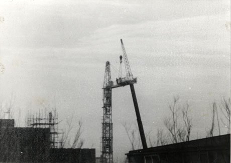 Photograph of the outline of the top of two large buildings, under construction, with the upper part of two large cranes in the centre of the photograph; the photograph has been identified as showing the Fine Fare Superstore at Peterlee under construction