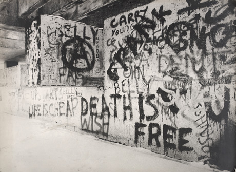 Photograph of graffiti, presumably on the structure in pete0087 and pete0088, described as Steps Over Sunny Blunts Pool, as the graffiti is on large blocks of concrete; it includes the symbol of the Campaign For Nuclear Disarmament, the phrases Life is Cheap, Death is Free and random words, such as Frank, Carry, Belly Johnson, and so on