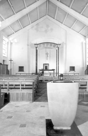Photograph showing the interior of a church looking towards the altar, which has a canopy over it; the font can be seen in the foreground of the photograph; the style of the building is plain and it was, most likely, built in the 1950s or 1960s; it has been identified as St. Cuthbert's Church, Peterlee