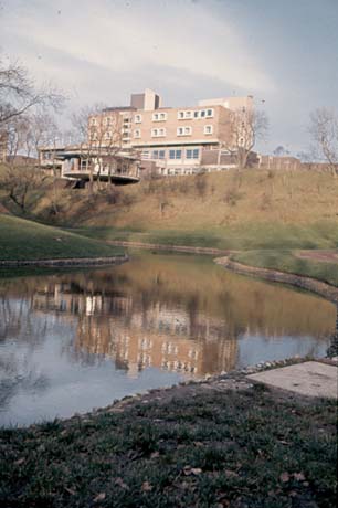 Photograph showing the circular room and the exterior of the brick building behind, that is, the Norseman Hotel (now Peterlee Lodge), seen close-up in 0169; the photograph is taken across a pond and hillside