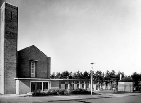 Photograph showing the exterior of the front of a brick building with a square tower on the left; a tall part of the building with a pitched roof and long window in the centre, and a single storey with six windows on the right; it has been identified as the Methodist Church, Peterlee