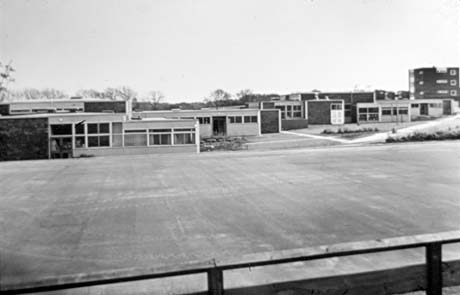Photograph of a series of low single-storey flat-roofed buildings of large windows, photographed from across a playground; they have been identified as North Blunts Infants and Junior School, Peterlee