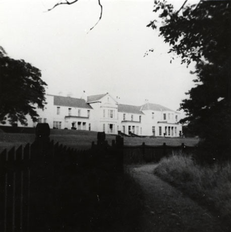 Photograph of the front of Seaham Hall in the distance with trees and lawns in front of it; the facade features two bay windows and three pillared entrances; Seaham Hall has been described as being a sanatorium at the time of the photograph