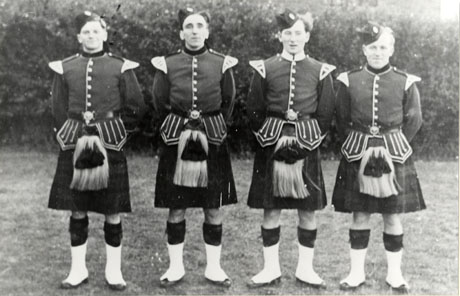 Photograph of four men dressed in the uniform of a highland regiment with kilts, sporrans, spats and dress jackets; they have been identified as members of the Dawdon Church Brigade, Seaham