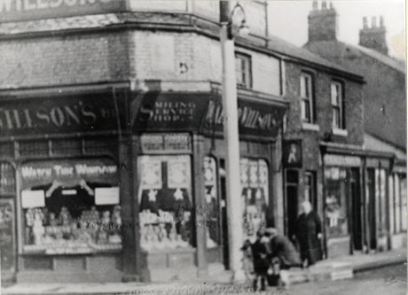 Photograph of the exterior of a shop belonging to Walter Willson's; the widows of the shop can be seen only indistinctly as can the three people on the pavement near the shop; the shop has been identified as Walter Willson's shop, North Railway Street, seaham