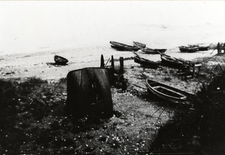 Photograph of eight small boats tethered on the shore; in the middle of the picture is a shield-shaped unidentified object; the photograph is somewhat indistinct and has been identified as Cobble House - The Blast, Seaham, 1932
