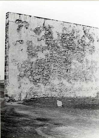 Photograph of the side of a high wall, made of stone and roughly rendered, standing on its own and identified as a Hand Ball Alley near Seaham Pit Yard, demolished in 1953
