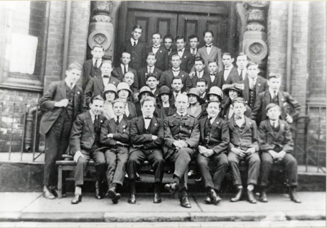 Photograph of thirty men and seven women posed in the doorway of a large building with Masonic symbols on its portals, identified as the Candlish Memorial Hall; one man on the front row is in uniform; all the rest of the group are in suits and ties; they have been identified as members of the Church Army