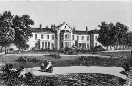 Photograph of an engraving of the front of a large building with central bay windows which are higher than the rest of the building, and four-pillared porches either side of the bays; there are lawns and paths in the grounds; the building has been identified as Seaham Hall