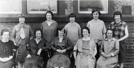 Photograph of ten women posed outside a brick building; five are standing and five sitting; they have been identified as the staff at Shotton Colliery Girls' School,including: Back Row, left: Miss Young; back row, right: Miss Stainthorpe; Front Row, right: Mrs. Hardy; front row, second right: Miss Warrenton