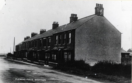 Photograph of block of ten terraced houses with bay windows, showing the front and end of the block; the houses have been identified as Fleming Field, Shotton