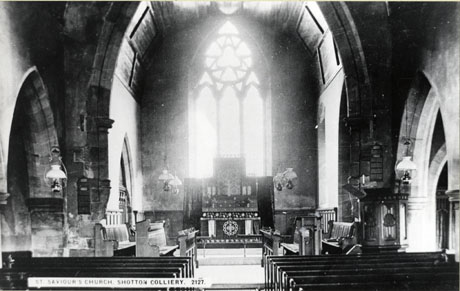 Postcard photograph entitled St. Saviour's Church, Shotton Colliery. 2127, showing the altar, chancel and the first five rows of pews; the church has hanging gas or oil lamps