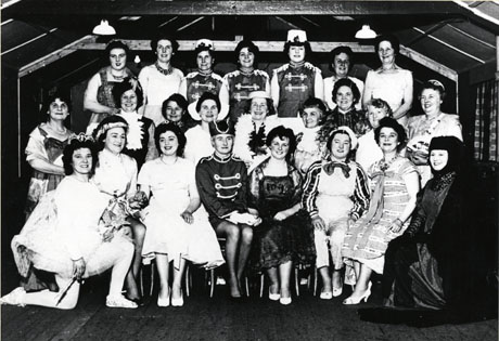 Photograph of twenty five women, members of the cast of Polly Flinders, a pantomime put on by the Women's Institute of Shotton Colliery; they are grouped possibly on the stage of a hall; their costumes include those of Ruritanian soldiers, ballet dancers, high class ladies and possibly cockneys