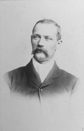 Photograph of the head and shoulders of a man with a moustache, wearing a dark jacket and a collar and tie; he has been identified as Mr. Parkin, First Undermanager, Shotton
