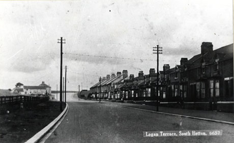 Postcard photograph entitled Logan Terrace, South Hetton. 6657, showing a wide tarmacadamed road running away to the right towards the horizon; on the right are two terraces of bay-windowed houses; on the right there is a fenced field and a large building in the far distance; the photograph has been identified as Logan Terrace and Menzies Farm, South Hetton