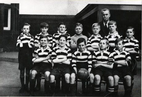 Photograph of twelve boys, aged approximately eleven years,in football strip, posed in a group with a man standing behind them; a boy on the front row is holding a football with the date 1933-4 on it; the group has been identified as South Hetton School Football Team