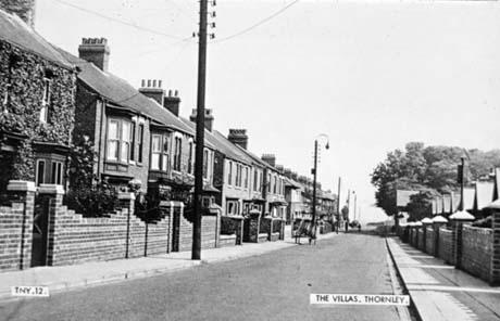 Postcard photograph entitled The Villas, Thornley. TNY. 12., showing a street lined with semi-detached houses, running away from the camera; the walls of the front gardens and the bay windows on the ground floor and the windows on the first floor can be seen