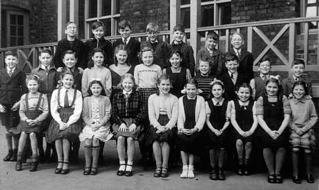 Photograph of twenty eight children, aged approximately nine years, grouped against the balcony of a building; they have been identified as pupils at the Junior School, Thornley