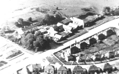 Photograph showing an aerial view of, on the right of the picture, seventeen semi-detached houses; beyond them in the centre of the picture is a group of larger buildings; beyond these buildings is open countryside; the photograph has been identified as Gore Hall Farm and the sites of Gore Hill and Gore Hall Estates, Thornley
