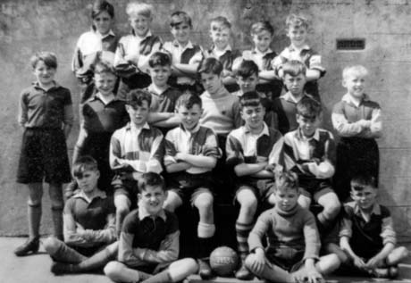 Photograph of twenty one boys, aged approximately ten years, wearing football strip, posed in front of a wall; they have been described as members of a school football team in Thornley; at the front of the group is a football bearing the figures 1953